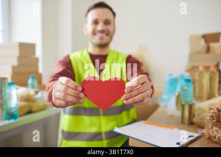 Soins bénévoles tenant le papier rouge amour, service de distribution de banque alimentaire dans une fondation caritative Banque D'Images
