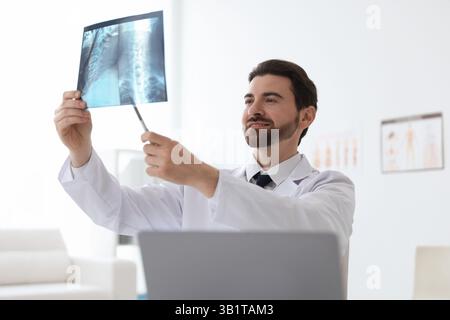 Médecin souriant examinant l'IRM du cou en clinique Banque D'Images