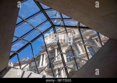Vue en bas angle du Palais du Louvre contre le ciel bleu clair vu à travers la lucarne pyramidale de verre du hall souterrain du Musée du Louvre. Paris, France. Banque D'Images