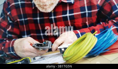 Électricien senior dénudage d'un fil, motif géométrique Banque D'Images
