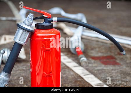 Cylindre d'extincteur rouge avec tuyaux d'incendie déroulés. Banque D'Images