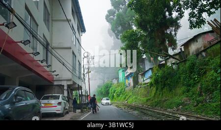 Kurseong, Bengale occidental, Inde - 10 août 2023 : maisons et une route en béton passant par les montagnes de l'Himalaya et la forêt verdoyante. Pittoresque naturel b Banque D'Images