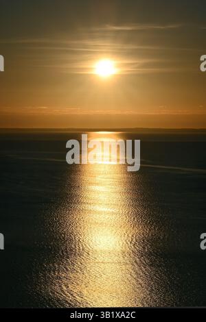 Reflets du soleil sur la surface tranquille de l'eau avec des ondulations subtiles au lever du soleil sur le lac Balaton, en format vertical Banque D'Images