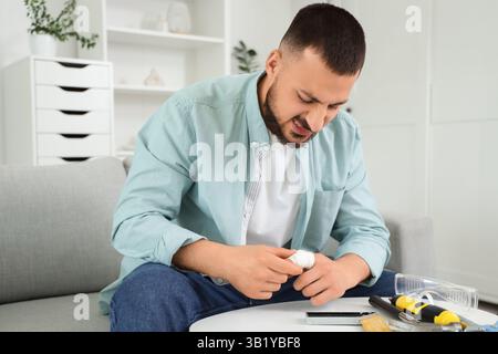 Jeune homme avec doigt bandé et outils de travail à la maison Banque D'Images