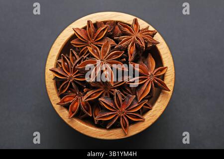 Étoiles d'anis aromatiques dans un bol sur une table sombre, vue de dessus Banque D'Images