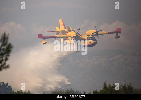 Un avion croate de lutte contre les incendies Canadair CL-415 lâche une grande charge d'eau au-dessus d'un feu de forêt. Banque D'Images