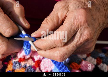 Image en gros plan d'une vieille femme avec des aiguilles à tricoter et de la laine Banque D'Images