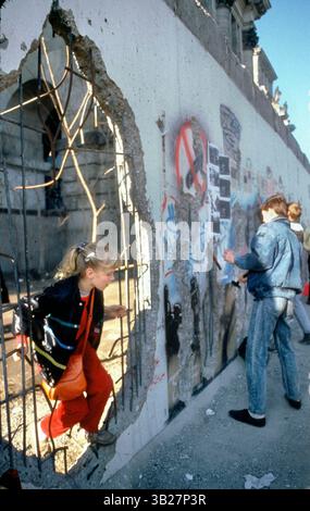 05 février 1990 - Berlin, Allemagne - Une fille grimpe à travers un grand trou du mur de Berlin, devant le Reichstag, à Berlin, Allemagne. Une section du mur de Berlin-Ouest a été démolie permettant aux gens de se promener dans Berlin-est. Le 9 novembre 2009 marquera le 20e anniversaire de la chute du mur de Berlin. (Crédit image : © Deirdre Hamill/ZUMA Press) Banque D'Images