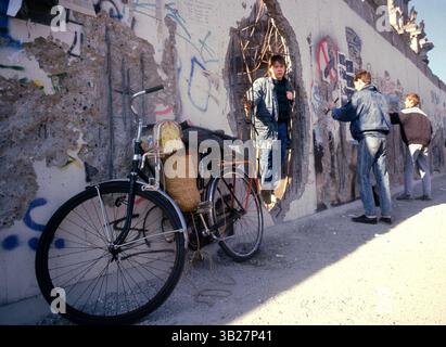05 février 1990 - Berlin, Allemagne - Un garçon traîne dans un trou du mur de Berlin, devant le Reichstag, à Berlin, Allemagne. Une section du mur de Berlin-Ouest a été démolie permettant aux gens de se promener dans Berlin-est. Le 9 novembre 2009 marquera le 20e anniversaire de la chute du mur de Berlin. (Crédit image : © Deirdre Hamill/ZUMA Press) Banque D'Images