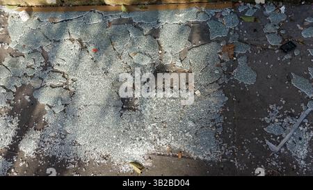 Une grande feuille de verre s'est désintégrée et s'est fissurée en petits morceaux sur un trottoir. Banque D'Images