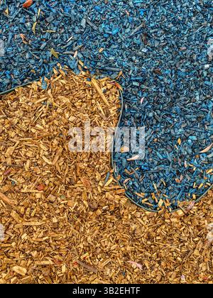 Vue de dessus du paillis de copeaux de bois jaune et bleu avec bordure incurvée, surface texturée naturelle pour l'aménagement paysager, le jardinage et la conception de terrains de jeux Banque D'Images