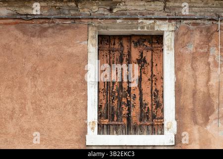 Vieille fenêtre avec volets en bois fortement altérés et texture murale rustique Banque D'Images