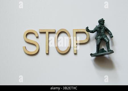 Mot STOP fait de lettres en bois et soldat en plastique vert sur fond blanc, concept contre la guerre, STOP guerre Banque D'Images