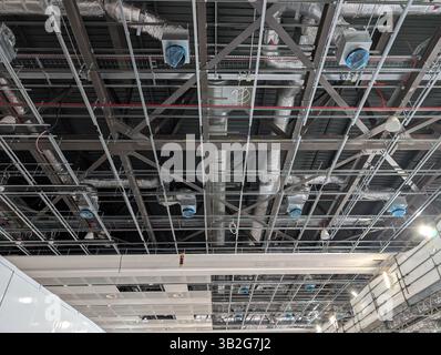 Plafond exposé industriel en construction, avec gaines HVAC, câblage électrique, tuyauterie et cadre de grille de plafond suspendu. L'image sho Banque D'Images