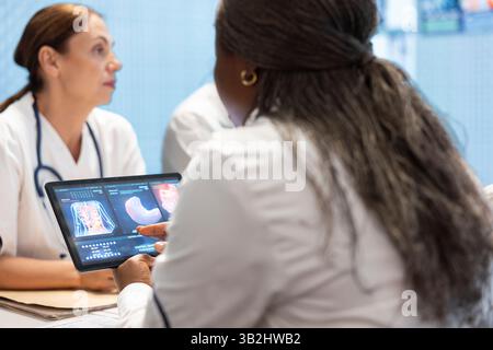 Les professionnels de santé en réunion examinant les organes sur les résultats de la tomodensitométrie. Des médecins et des radiologues qualifiés examinent les radiographies et les dossiers hospitaliers pour élaborer des plans de traitement efficaces. Travail collectif. Banque D'Images