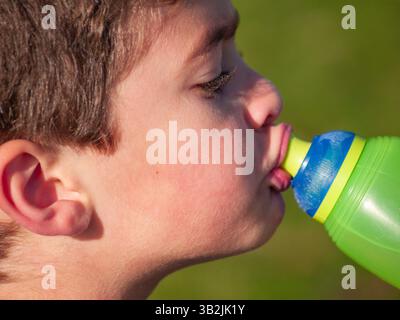 Auckland Nouvelle-Zélande - 12 mai 2012 ; gros plan d'un garçon avec bouteille de boisson verte et bleue jusqu'à lèvres buvant. Banque D'Images