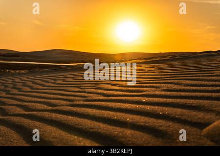 Belle vue sur le désert de sable au coucher du soleil. Conception de bannière. Une aube orange jaune vif dans le désert. Banque D'Images