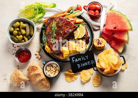 Côtes de barbecue avec légumes, sauce, maïs rôti et pastèque sur fond blanc. Vue de dessus. Banque D'Images