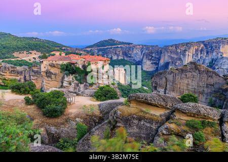 Meteora, Grèce. Formations rocheuses de grès et monastère Varlaam au lever du soleil. Banque D'Images