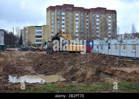 Excavatrice creusant le sable dans le camion à benne basculante dans le grand chantier de construction. Banque D'Images