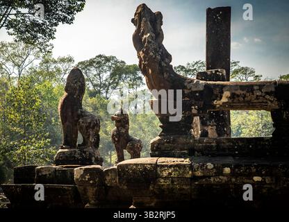 Anciennes ruines en pierre avec des sculptures complexes, avec des statues de lion et de créature mythiques au milieu d'une végétation luxuriante. La scène capture une atmosphère sereine Banque D'Images