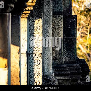 Sculptures en pierre complexes sur d'anciens piliers de temple illuminés par la lumière du soleil, présentant des motifs et des textures détaillés. Banque D'Images