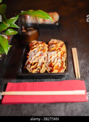 Un plateau de sushis magnifiquement arrangé accompagné de baguettes et d'une serviette rouge éclatante, habilement placé sur une table en bois Banque D'Images