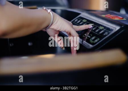 Un gros plan montre la main d'une femme ajustant la vitesse sur un tapis roulant, indiquant une concentration sur la forme physique, les routines saines, et l'intégration technologique dans Banque D'Images