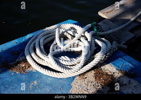bobine de corde blanche sur le côté du quai avec de l'eau en arrière-plan Banque D'Images