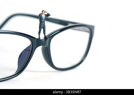 Hommes d'affaires utilisant des jumelles debout au-dessus des lunettes. Miniature Tiny People Toys Photography. isolé sur fond blanc. Photo d'image Banque D'Images