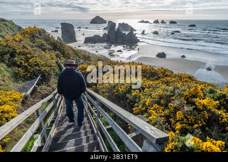 L'homme descend jusqu'à l'océan sur les escaliers menant à la plage de Bandon, Oregon. Banque D'Images