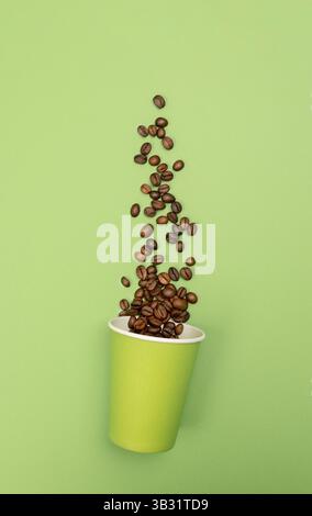 Haricots dispersés à partir d'un gobelet à sac en papier ouvert sur une image verte et plate destinée à des applications commerciales ou promotionnelles Banque D'Images