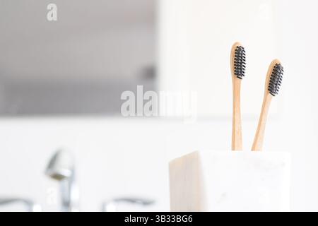 Deux brosses à dents en bambou dans une tasse sur le lavabo de la salle de bain Banque D'Images