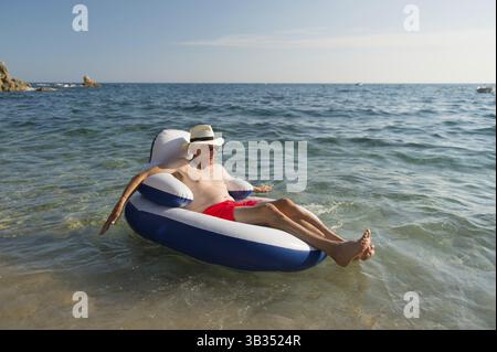 Senior en vacances flottant à la présidence dans la mer Banque D'Images