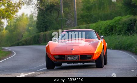 Whittlebury,Northants.,.UK - 27 avril 2025 : voiture Corvette Stingray orange 1975 conduite sur une route de campagne anglaise. Banque D'Images