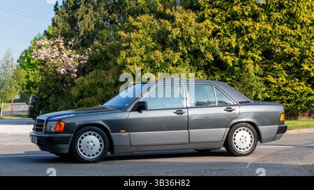 Whittlebury,Northants.,.UK - 27 avril 2025 : 1990 Mercedes Benz 190e voiture conduisant sur une route de campagne anglaise. Banque D'Images