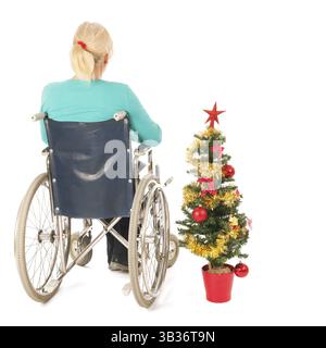 Femme blonde en fauteuil roulant avec isolé de l'arbre de Noël sur fond blanc Banque D'Images