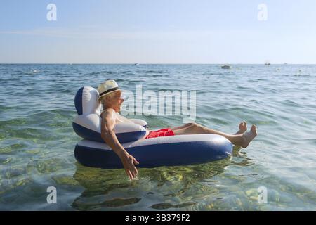 Senior en vacances flottant à la présidence dans la mer Banque D'Images