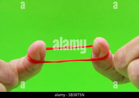 Deux doigts étendant un élastique rouge Banque D'Images