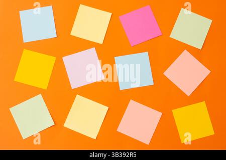 Papiers de notes colorés, collection de différentes feuilles colorées sur fond orange, texte de votre message, rappel Banque D'Images