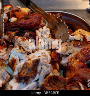 Gros plan de viande de canard rôtie exposée dans un récipient en métal argenté lors d'un buffet chinois, montrant une texture juteuse et une peau croustillante. Banque D'Images