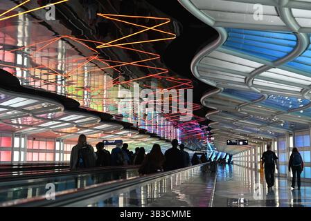 Une sculpture cinétique au néon et des panneaux colorés distraient les passagers dans le long tunnel de connexion entre les terminaux B et C de l'aéroport O'Hare de Chicago Banque D'Images