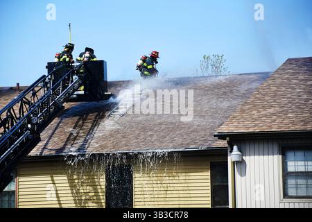 RACE : un incendie de maison menace de se propager à celui des maisons voisines alors que l'équipe d'intervention d'urgence travaille dur pour protéger la communauté du danger. Banque D'Images