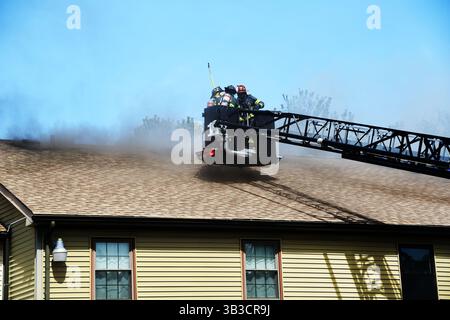 RACE : un incendie de maison menace de se propager à celui des maisons voisines alors que l'équipe d'intervention d'urgence travaille dur pour protéger la communauté du danger. Banque D'Images
