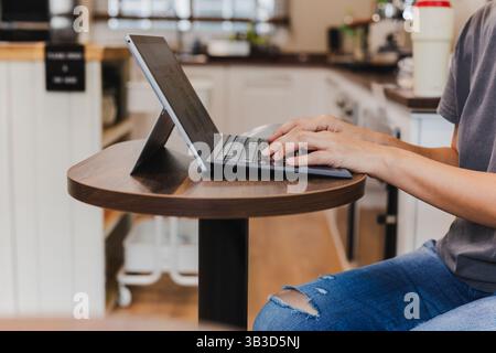 Femmes mains tapant sur le clavier d'ordinateur portable dans le café. Banque D'Images