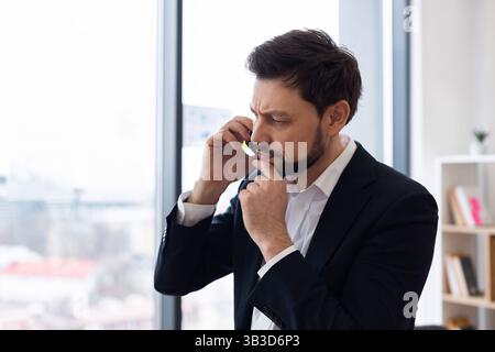 Homme d'affaires dans le bureau pensant tout en parlant au téléphone près de la grande fenêtre Banque D'Images