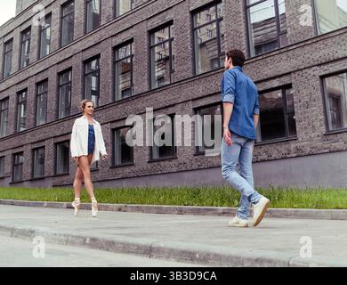 un partenaire amoureux rencontre une ballerine dans une rue de la ville tout en se promenant dans la ville un jour d'été Banque D'Images