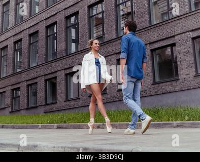 un partenaire amoureux rencontre une ballerine dans une rue de la ville tout en se promenant dans la ville un jour d'été Banque D'Images