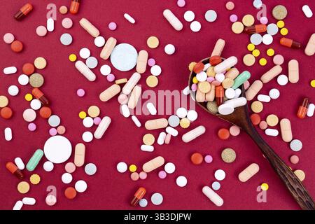 Colorés différents comprimés et gélules dans une cuillère de bois. L'industrie pharmaceutique mondiale pour des milliards de dollars par année. Les médicaments pharmaceutiques. Isolé sur Banque D'Images