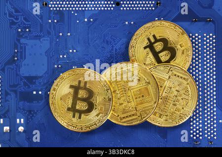 Cryptocurrency virtuelle Bitcoin argent pièces d'or sur un ordinateur à circuit imprimé (PCB). L'avenir de l'argent. L'équipement informatique. La mère b bleu Banque D'Images
